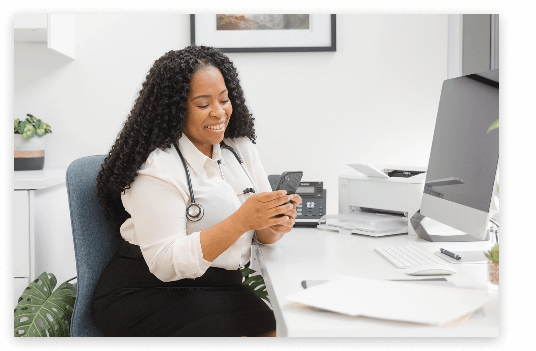 A doctor in her office checks her mobile phone.