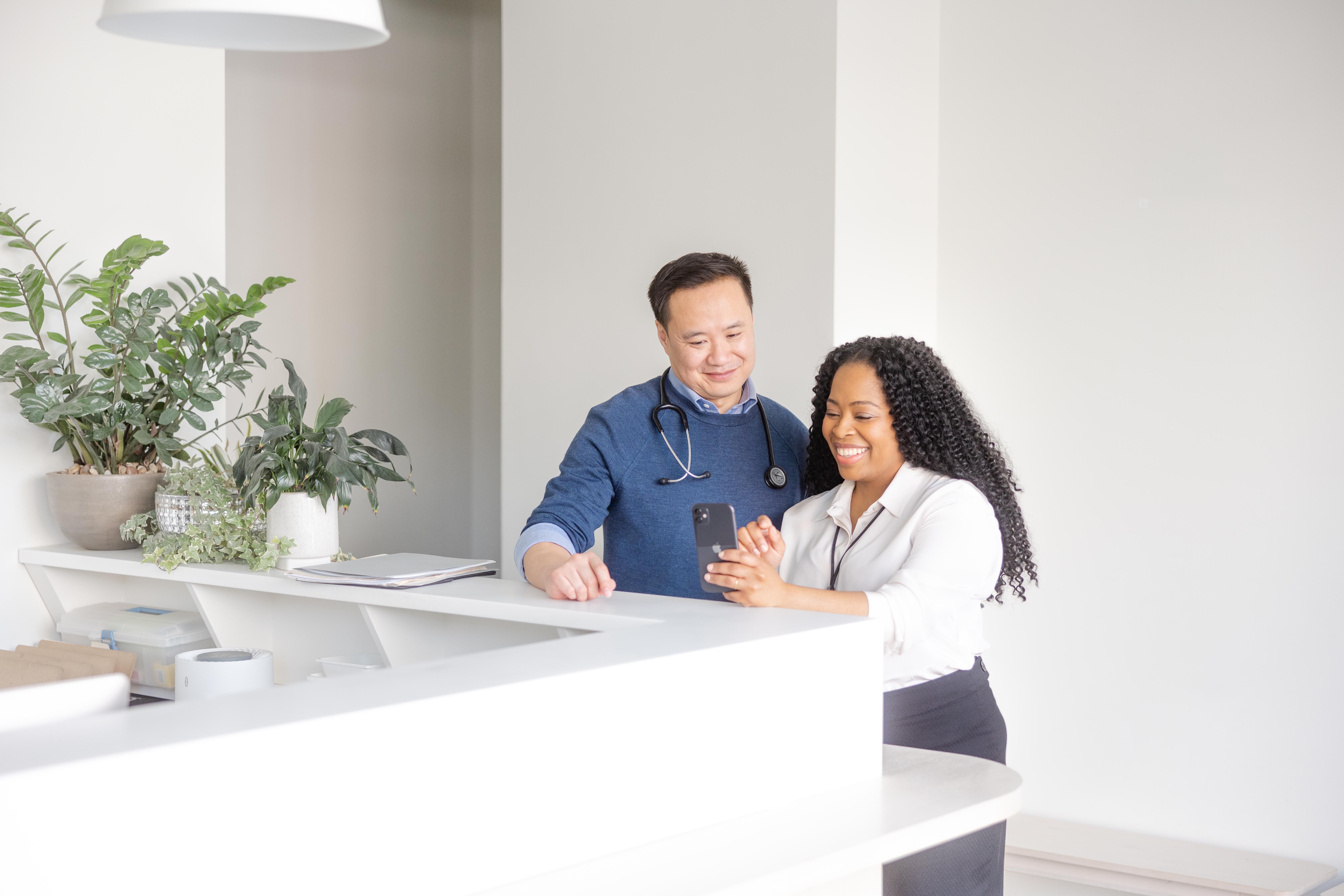 A physician and medical practitioner reviewing patient information on a smart phone.